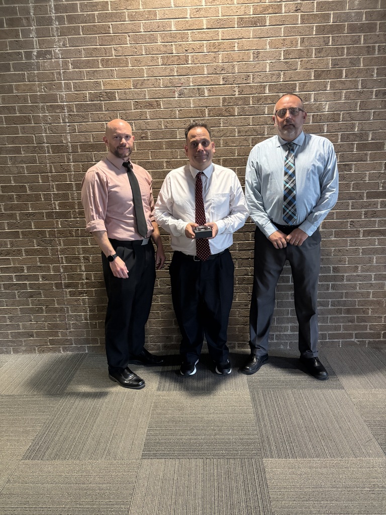 Three people posing by lobby wall