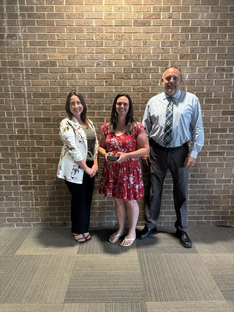 Three people posing by lobby wall