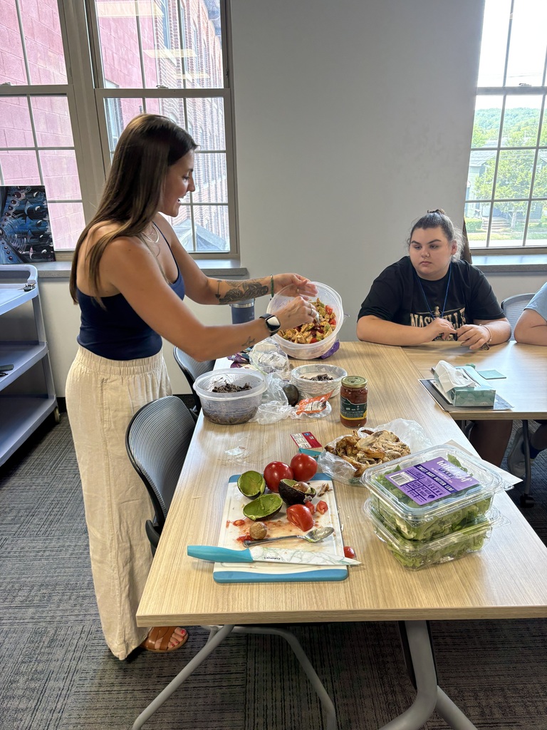 Person serving food as another person sitting at table looking on
