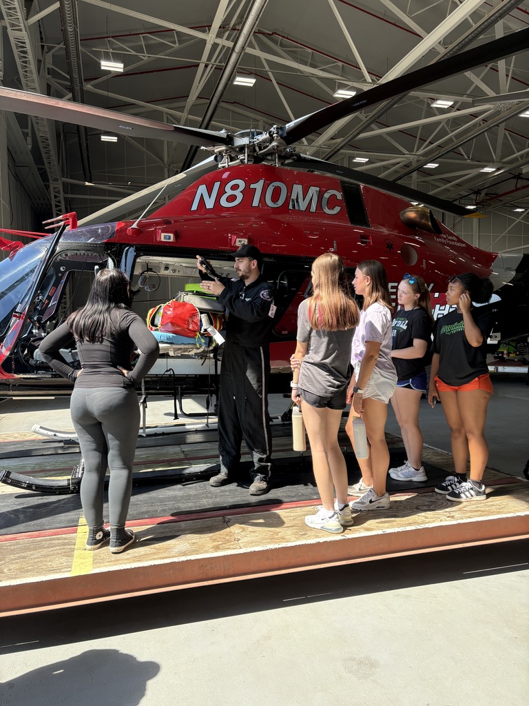 Students and a professional standing outside a helicopter talking about it