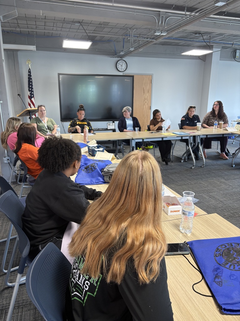 emergency services professionals sitting at tables for a panel discussion and students sitting at tables listening