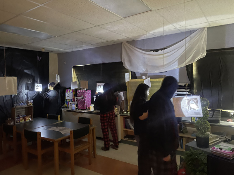 Students going through a classroom Holocaust museum with flashlights