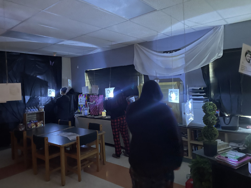 Students going through a classroom Holocaust museum with flashlights