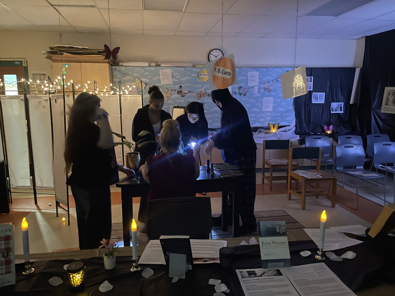 Students going through a classroom Holocaust museum with flashlights