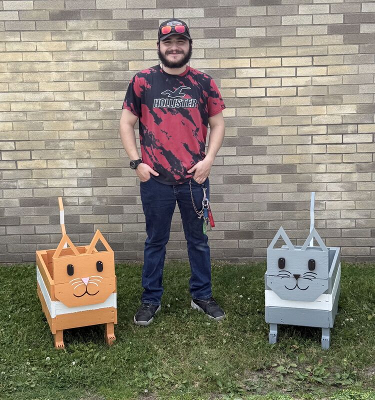 Student poses with two cat-themed flower boxes