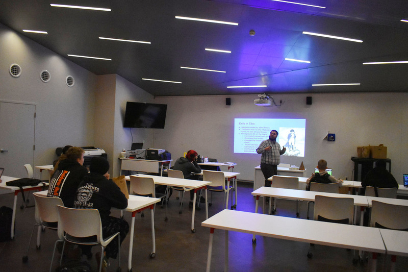 VP-TECH students at tables in classroom listening to history teacher presenting