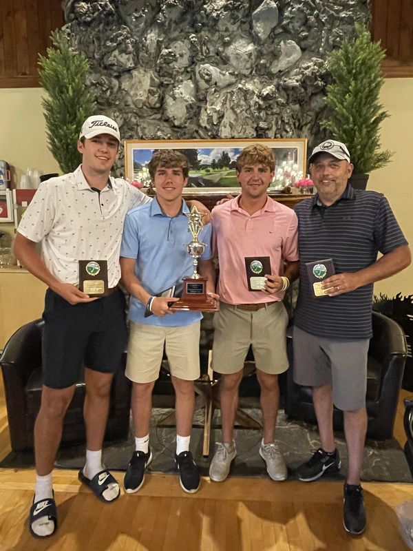 Four golfers including District Superintendent D.J. Shepardson holding plaques and trophy