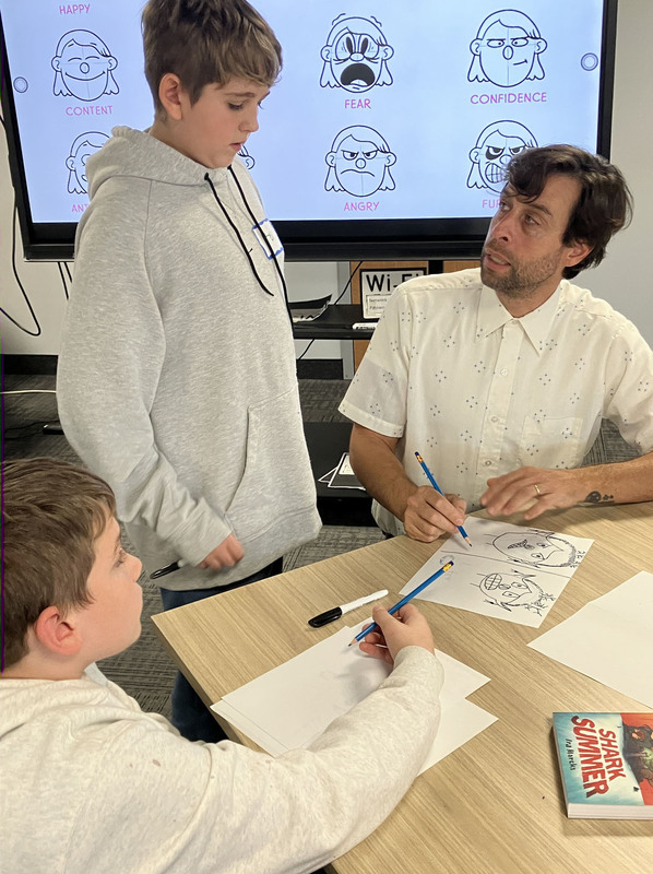 Graphic novelist Ira Marcks drawing and talking to two students