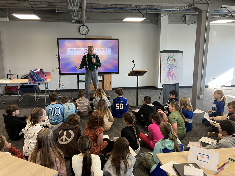 Author speaking to students who are sitting on the floor