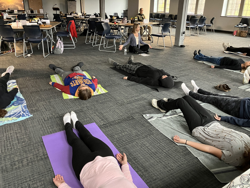 Students doing yoga with wellness instructor in front