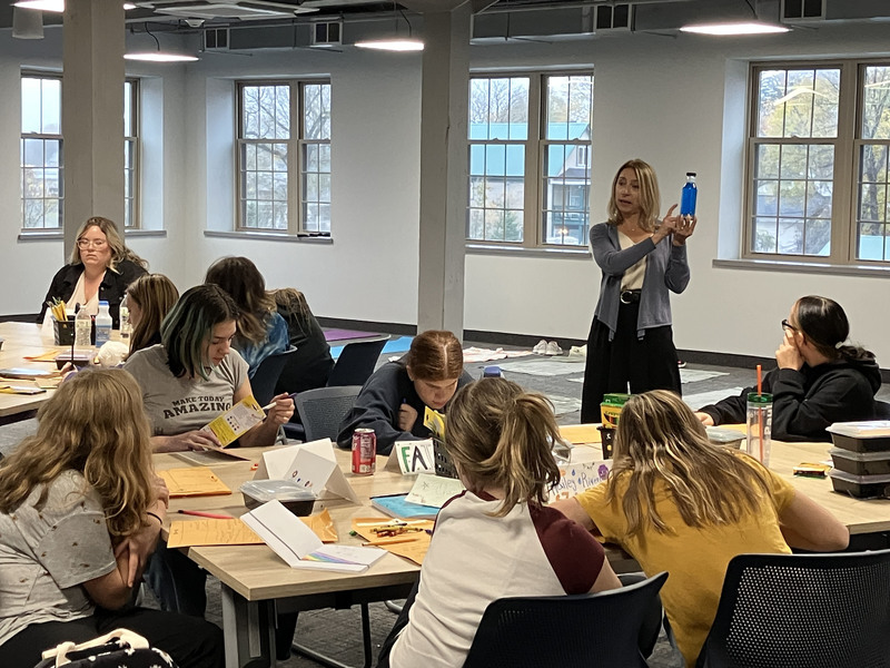 SEL/mindfulness consultant holding a bottle and students at work