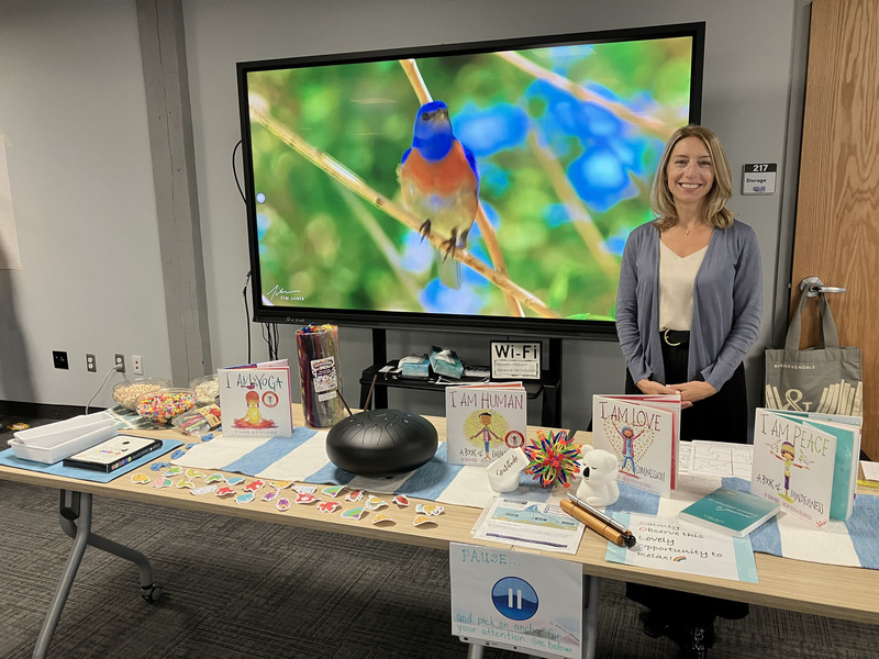 SEL/mindfulness consultant posing at her table with books and other materials