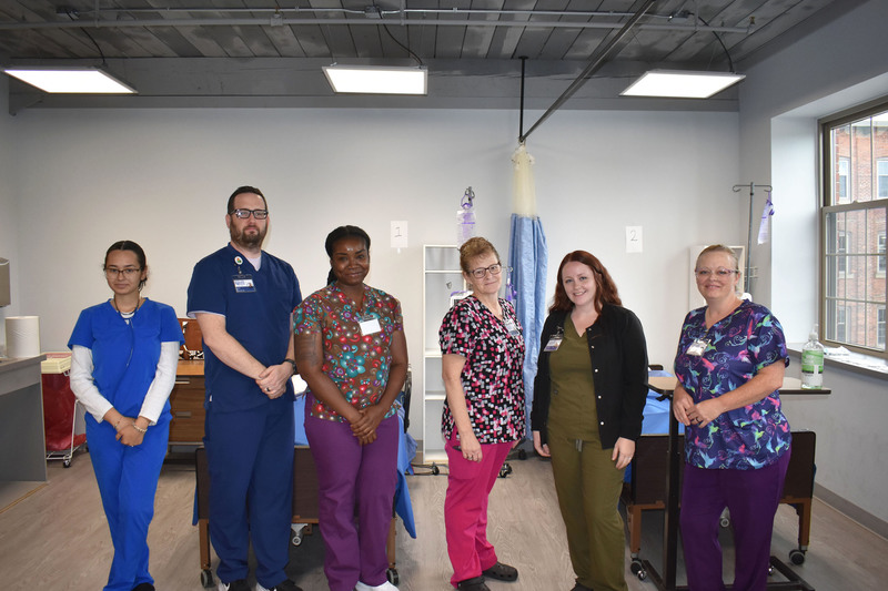 Six adult LPN students posing in a nursing lab