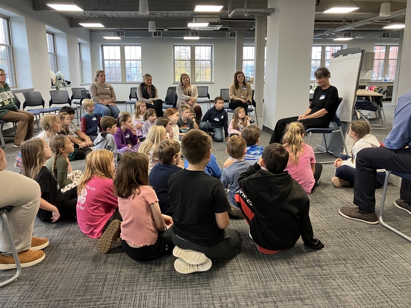 Students sitting on the floor listening to storyteller Regi Carpenter
