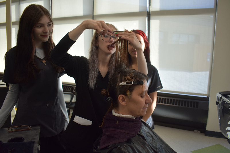 Student cutting mother's hair as two other students look on