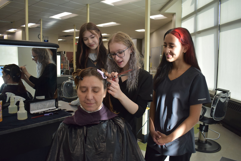 Student cutting mother's hair as two other students look on