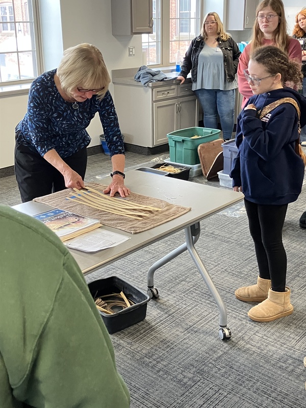 Artist showing student how to make a basket
