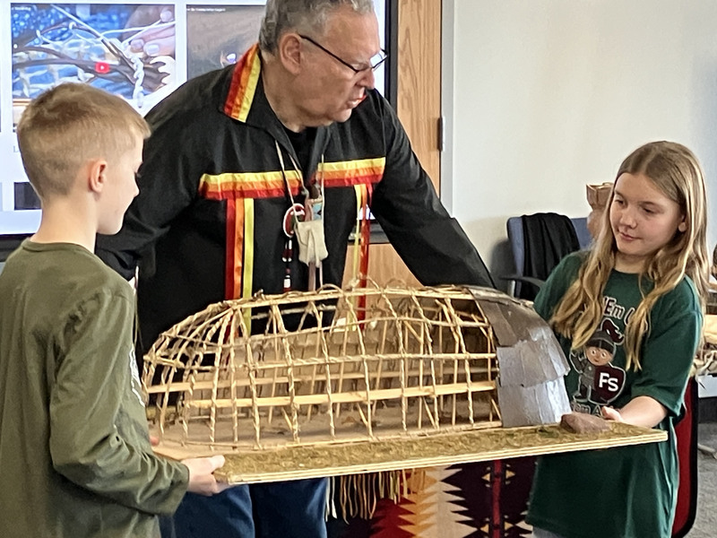 Randy Phillips and two students holding a display