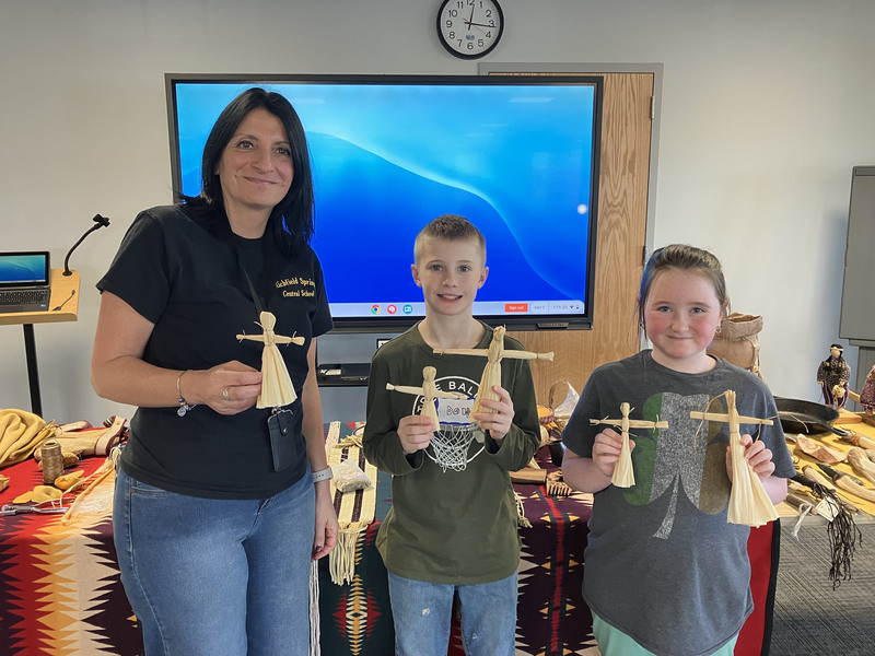 Two students and adults posing with Iroquois items
