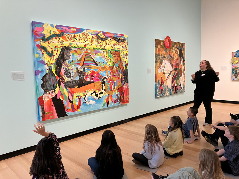 Students and guide looking at art display at art museum