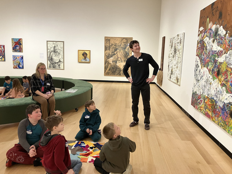 Students and guide looking at art display at art museum