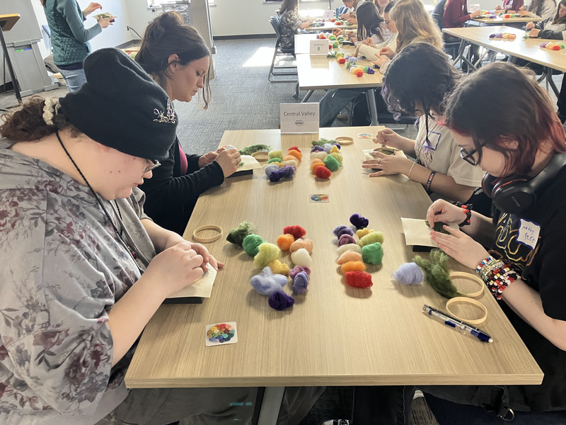 Four students needle felting at a table
