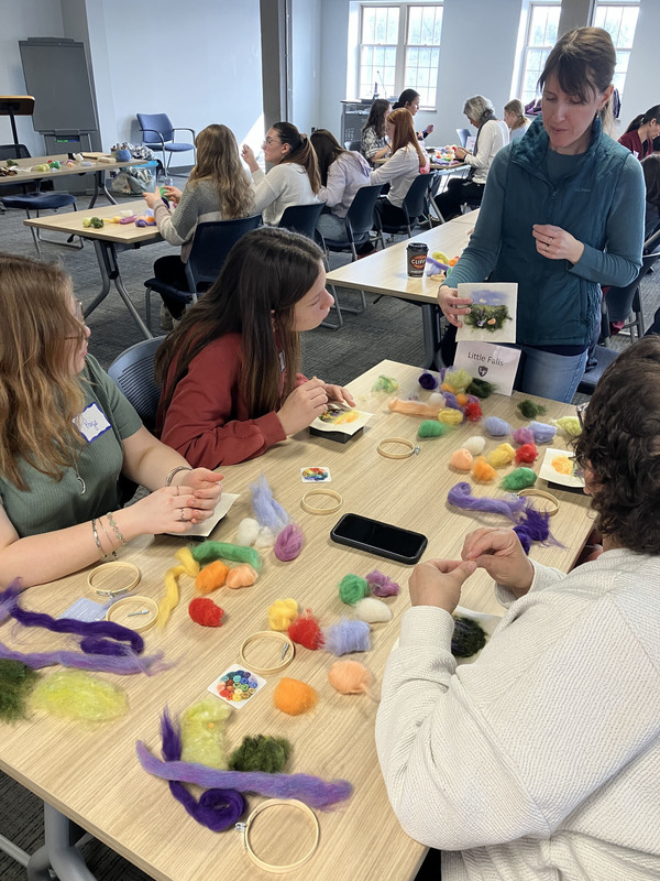 Students working on needle felting as artist stands by table
