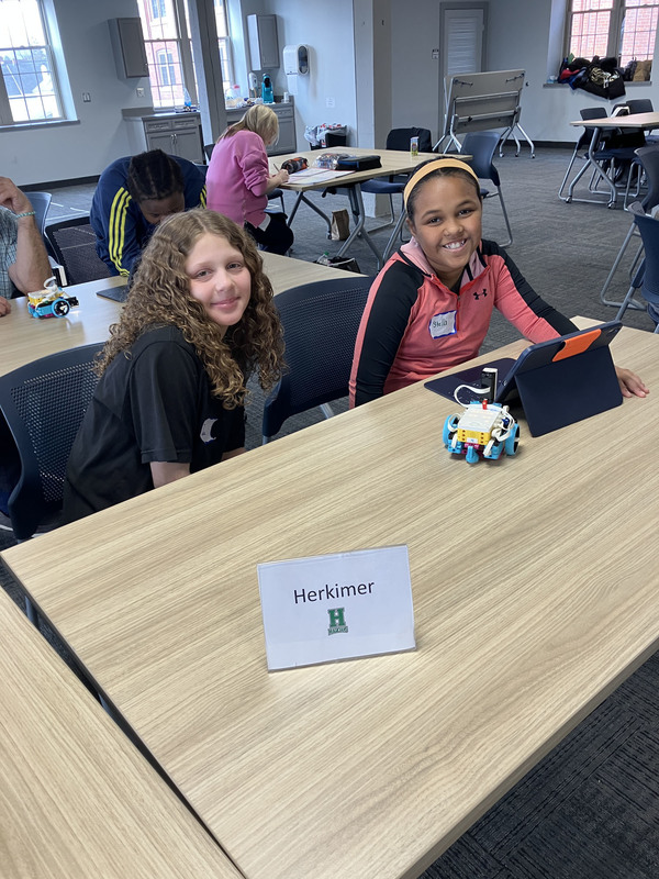 Students at table with tablet and robot