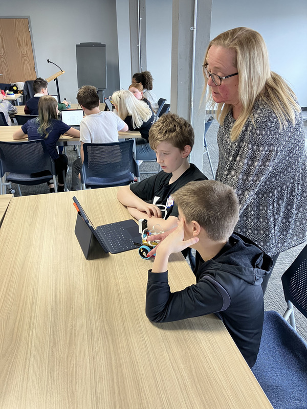 Students working on tablet as presenter looks on