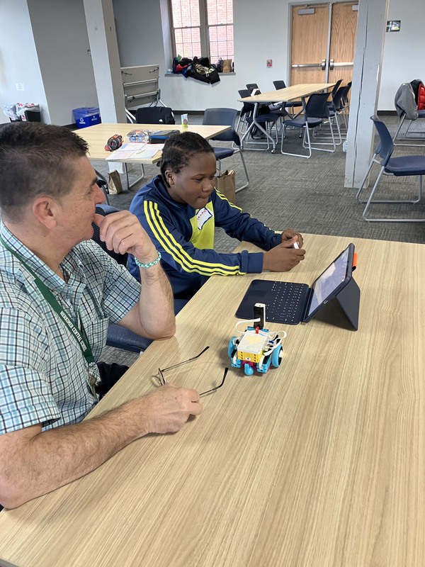 Staff member and student working on tablet to program a robot