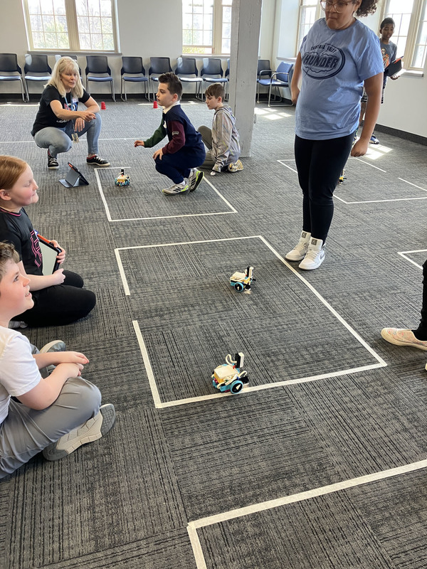 Many Students on floor using tablet by robot