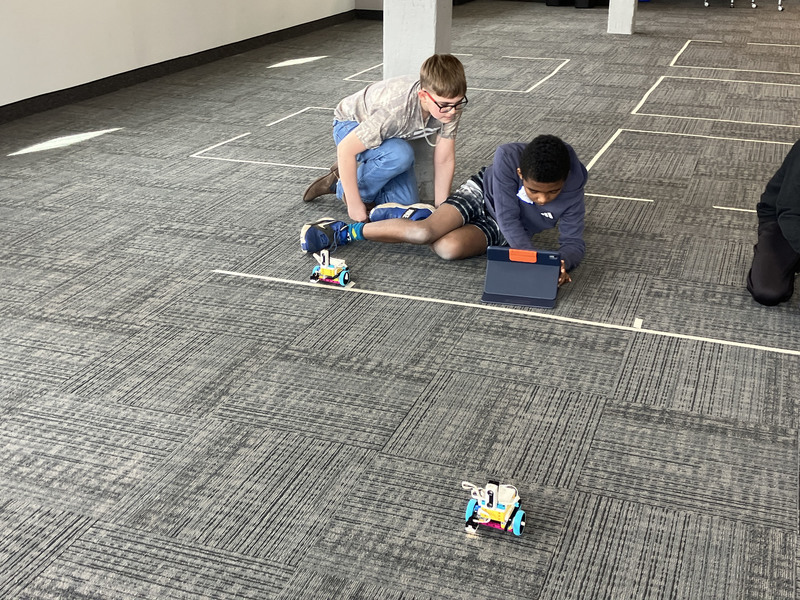 Students on floor using tablet by robot