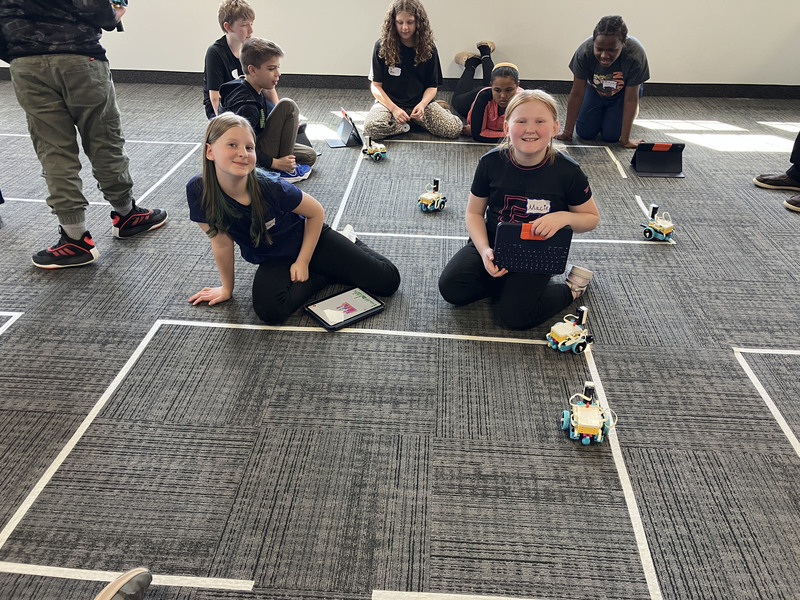 Many Students on floor using tablet by robot