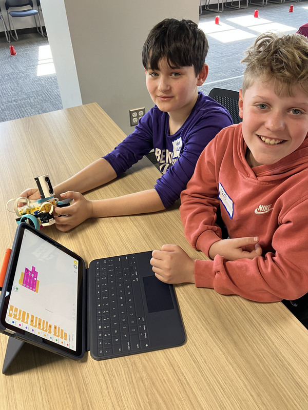 Students at table with tablet and robot