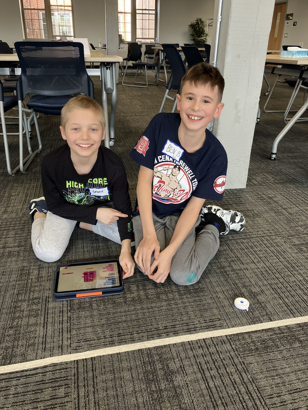 Students on floor with tablet and robot