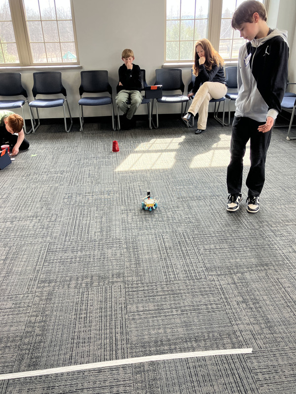 Students workign with robots as staff look on