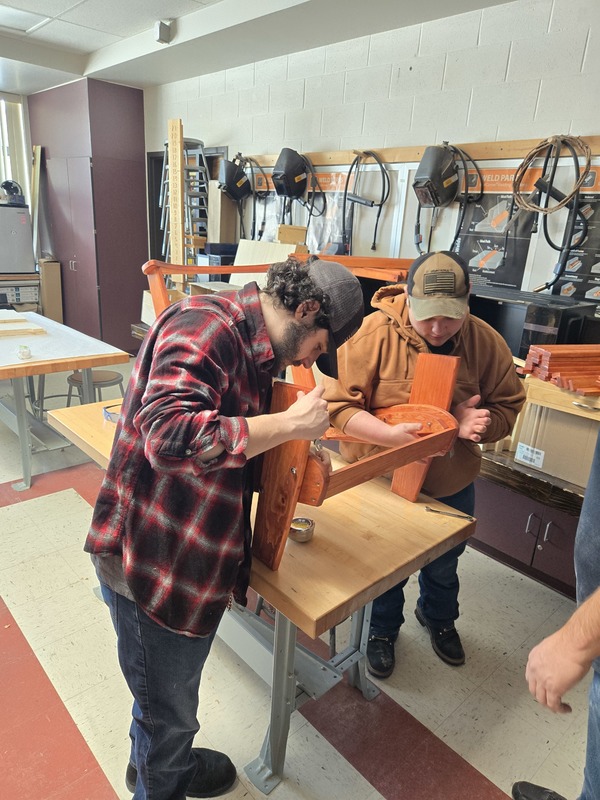 Two Pathways students look over an Adirondack chair