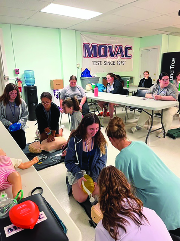 Students practicing CPR in a classroom with MOVAC