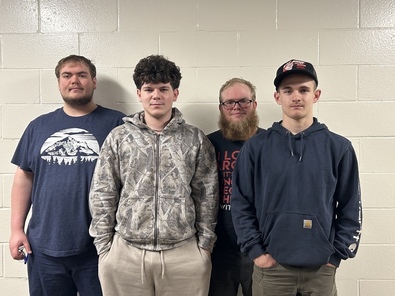 Four students posing together in front of a wall