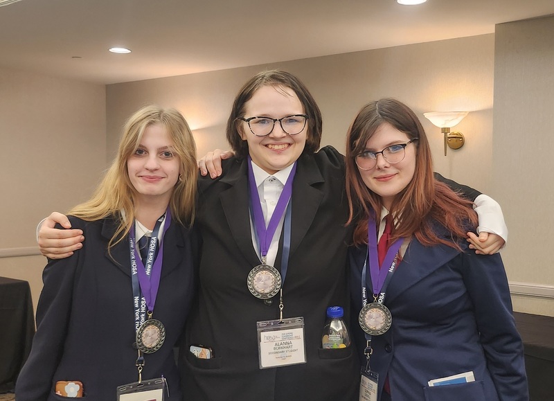 Three students pose wearing award medals at HOSA conference