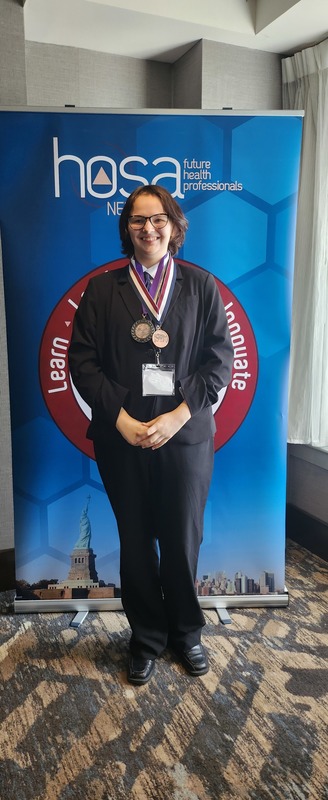 Student poses wearing award medals at HOSA conference
