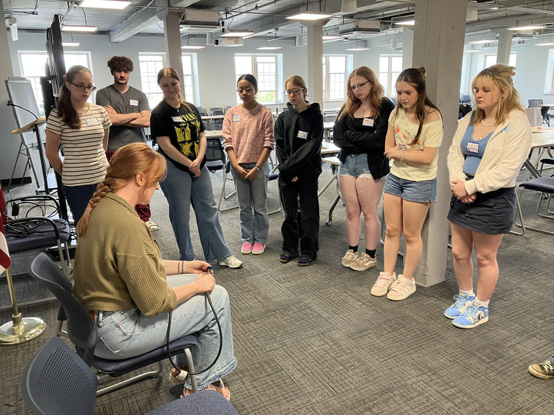 Artist sitting presenting to standing high school students