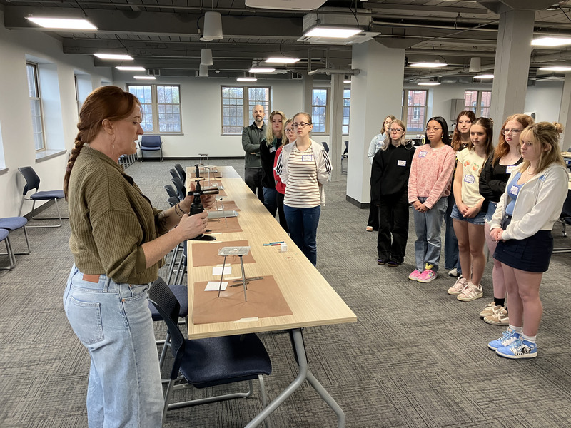 Artist standing presenting to standing high school students