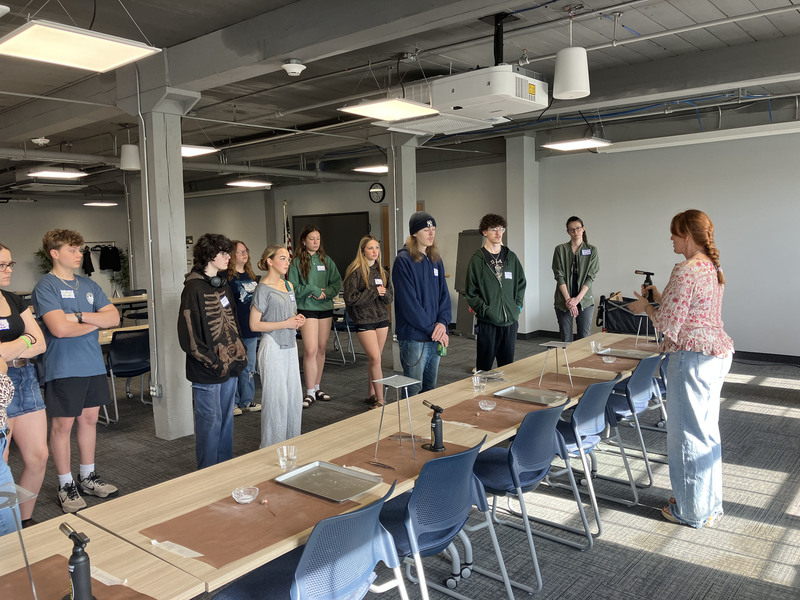 Artist standing presenting to standing high school students