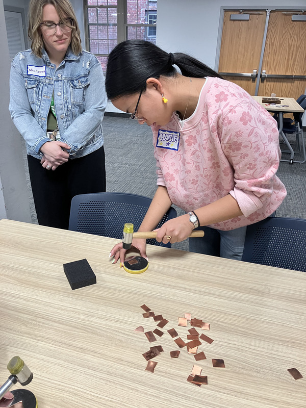 Student working on art/jewelry project as another person looks on