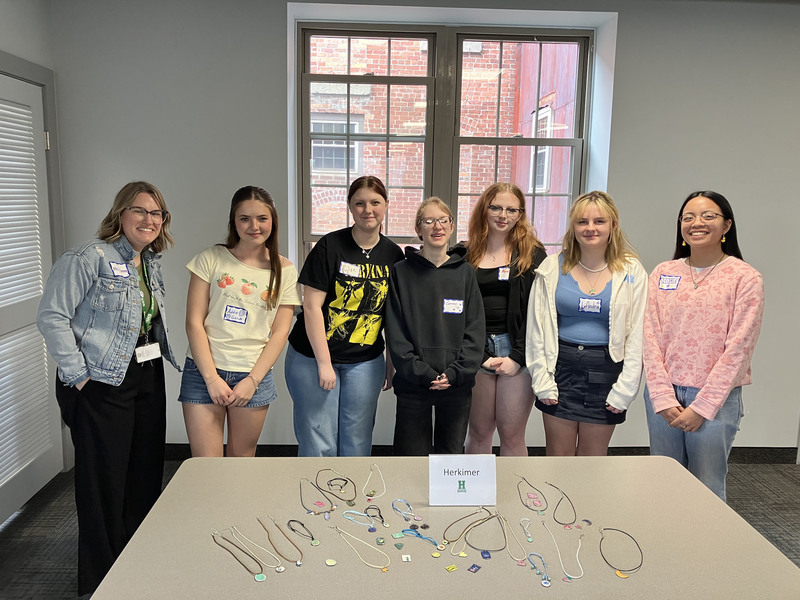 Seven people and a table full of jewelry they made