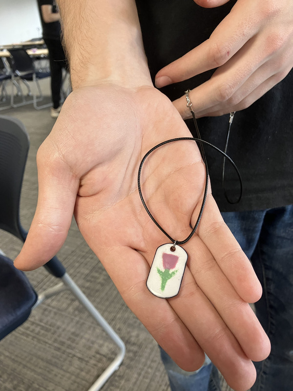 Hand holding a bracelet with a flower on it