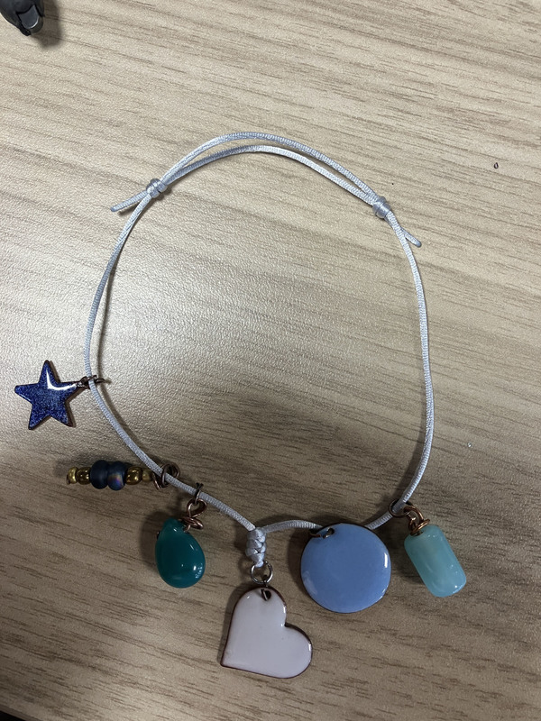 A blue bracelet with stars, hearts, circles and other shapes