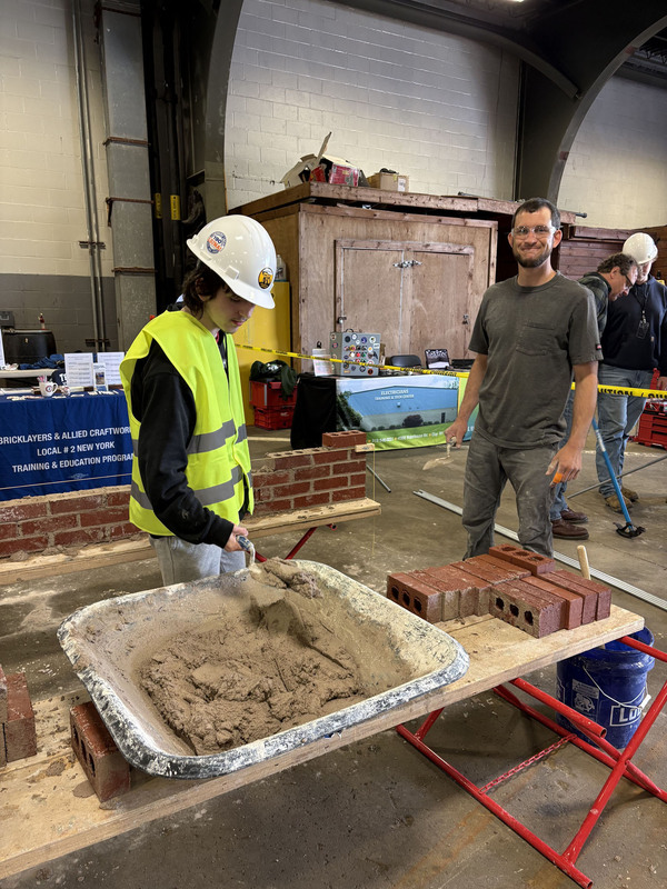 Student using cement with person looking on