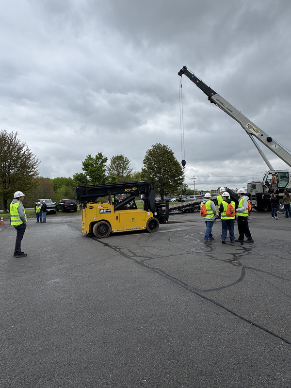 Students and others outside with construction vehicles including a crane